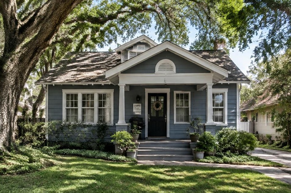 Blue-gray vintage bungalow shaded by mature oak trees