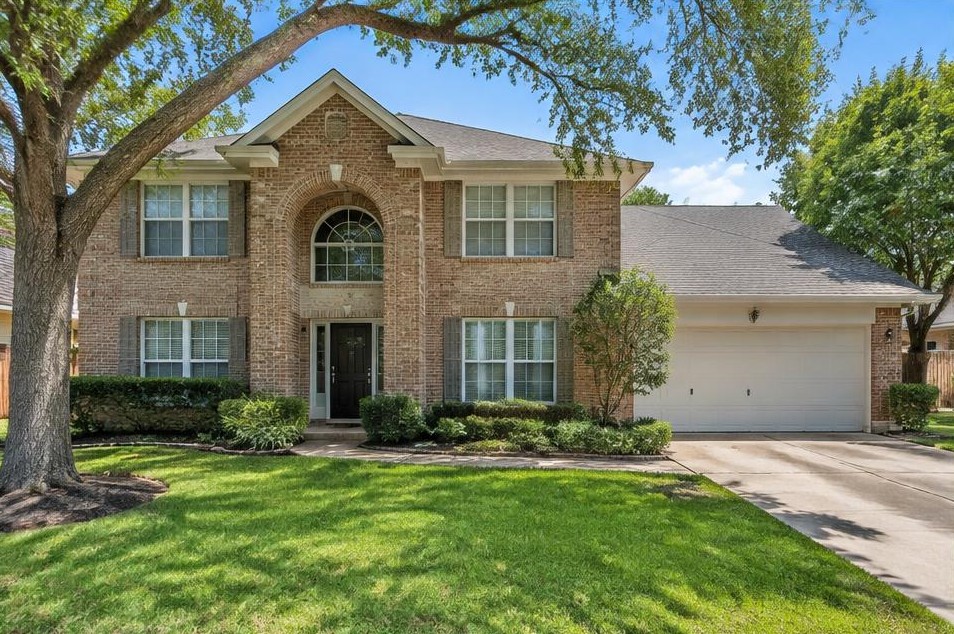 Two-story suburban brick family home with front lawn and white windows